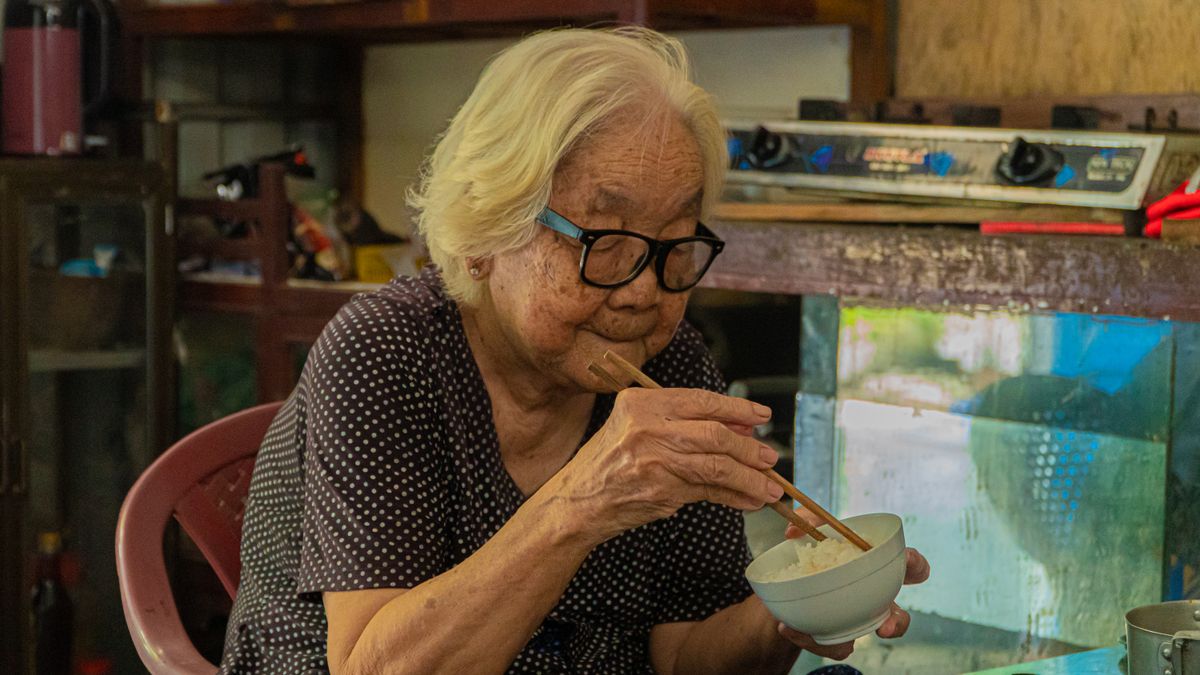 茶わんのご飯を少しずつ食べる高齢の女性